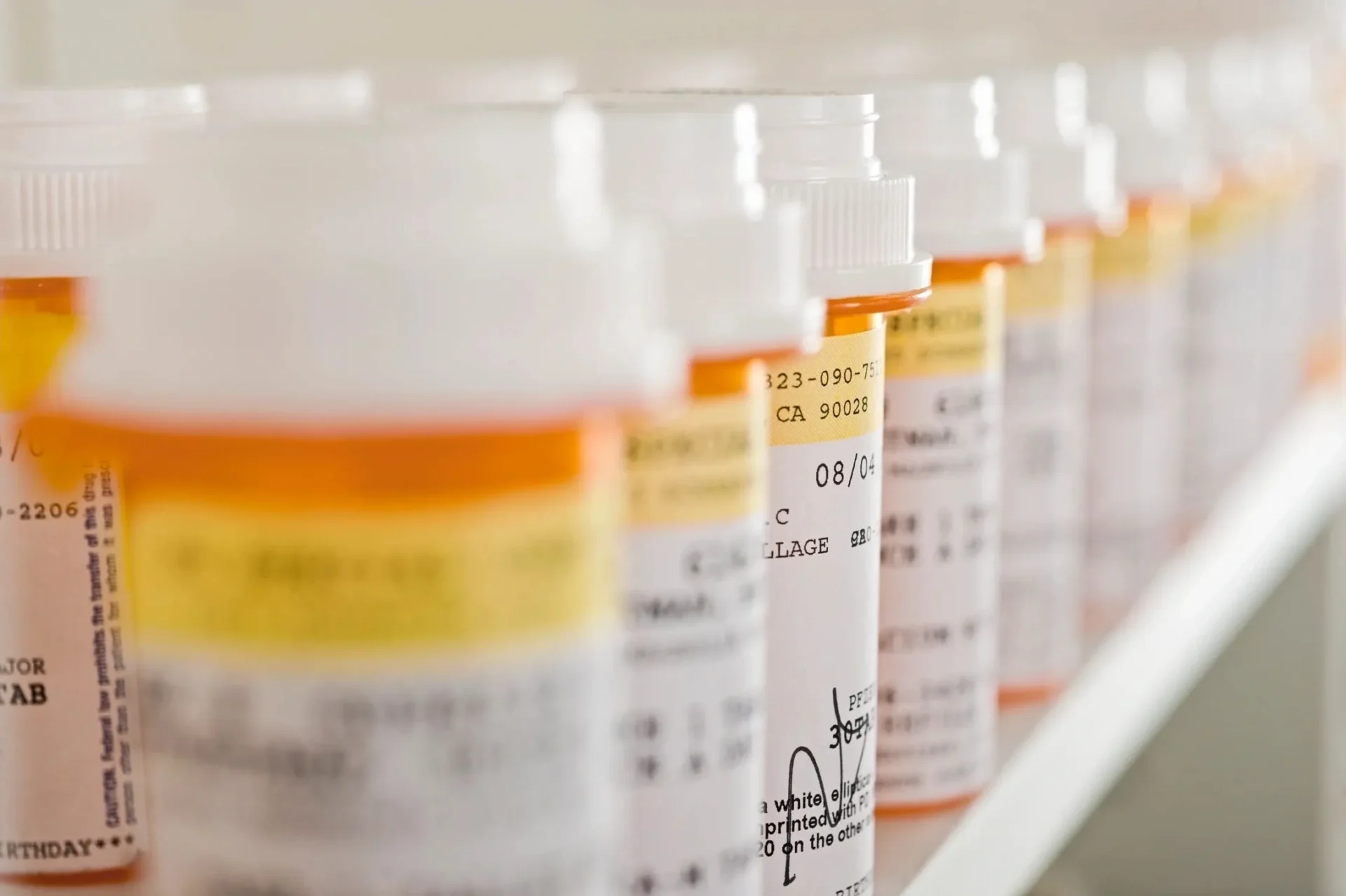 A row of prescription bottles lined up on top of each other.