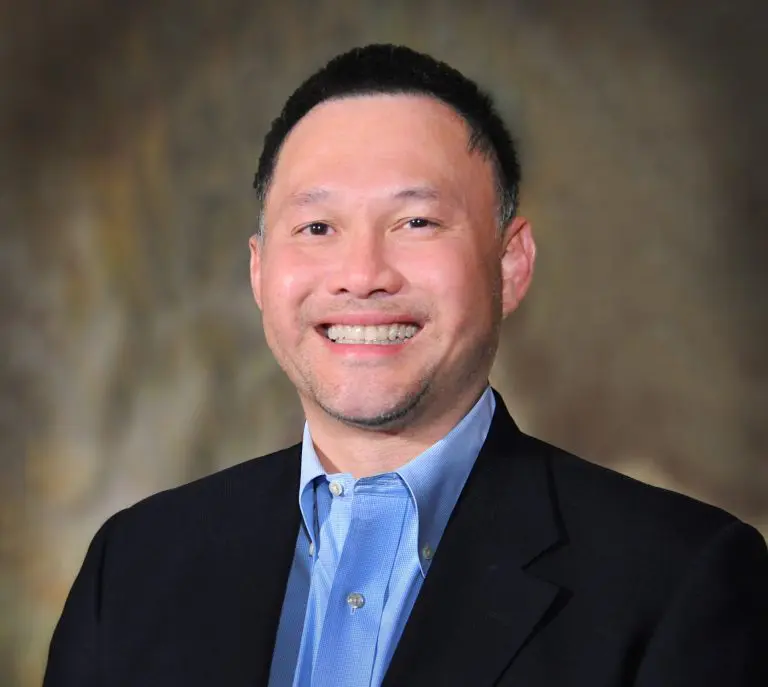 A man in a suit and tie smiling for the camera.